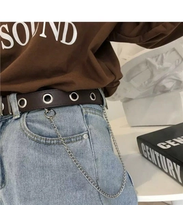 Close-up of brown leather belt featuring silver grommets and a stylish metal chain detail