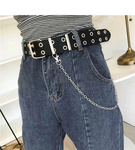 Detail of punk black waist belt with silver eyelets and metal chain on blue jeans
