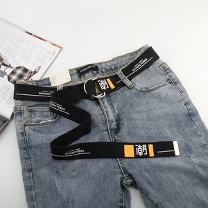 Detail of black canvas belt with double D-ring buckle and white text print on denim