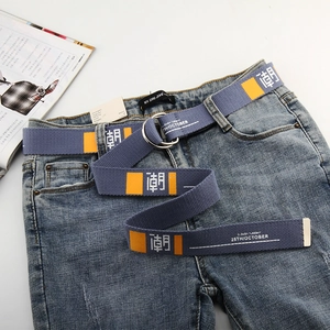 Detail of blue canvas belt with orange print and double D-ring buckle on jeans
