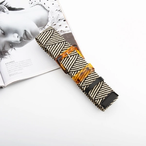 Detail view of woven striped belt with tortoise shell buckle on fashion magazine background