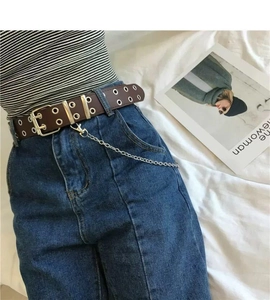 Close-up of brown punk belt with double eyelets and metal chain on blue denim jeans