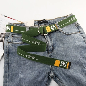 Detail of green canvas street style belt with metal double ring buckle on blue denim jeans
