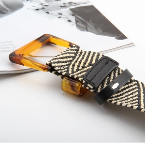 Macro detail of amber resin buckle and black-white chevron woven belt strap on magazine