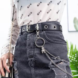 Detail of black leather punk belt with metal eyelets, silver bear pendant, and double chains