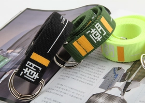 Close-up of stylish canvas belts with double D-ring metal buckles and letter prints