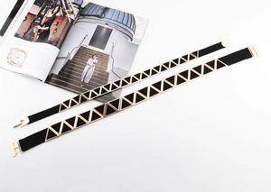 Détail de deux ceintures élastiques noires avec boucles triangulaires en métal doré