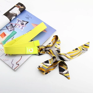 Détail de la ceinture en nylon jaune fluo avec patch marguerite et accessoire foulard en soie