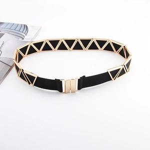 Détail d'une ceinture élastique noire ornée de triangles en métal doré et boucle élégante