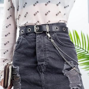 Detail of punk black leather belt with double metal chains on ripped denim skirt