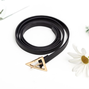 Cintura sottile in pelle nera da donna con fibbia triangolare dorata su sfondo bianco
