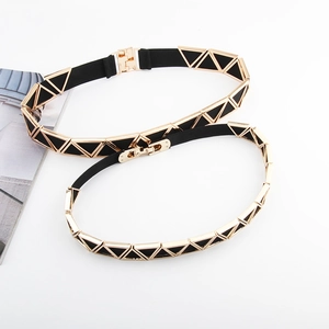 Détail d'une ceinture élastique noire avec boucles métalliques triangulaires dorées