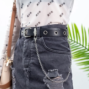 Detail of punk style black eyelet belt with silver metal chain on denim skirt