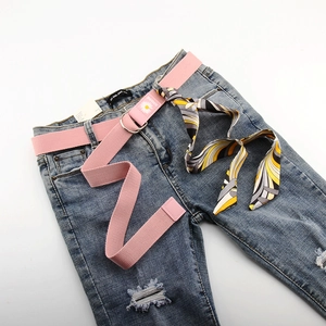 Ceinture rose en toile avec marguerites, boucles D et foulard sur un jean bleu