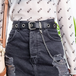 Detail of punk style black PU leather belt with metal eyelets and decorative silver chain