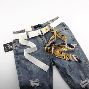 Détail d'une ceinture blanche en toile avec boucle en D, fleur de tournesol et foulard rayé