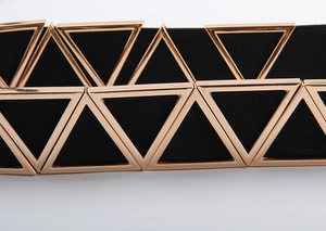 Détail d'une ceinture élastique noire avec boucle métallique triangulaire dorée entrelacée