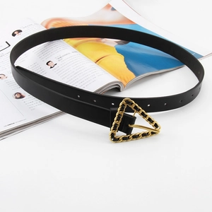 Ceinture femme en cuir noir avec boucle chaîne triangle en or mat sur un magazine