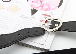 Détail d'une ceinture noire avec une boucle métallique argentée en forme de cœur pour femme