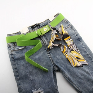 Détail d'un jean bleu clair avec ceinture en toile marguerite et foulard en soie