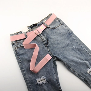 Détail d'une ceinture en toile rose avec broderie marguerite sur un jean en denim
