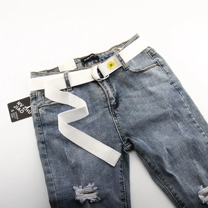 Détail d'une ceinture en toile blanche avec boucle en D et broderie tournesol