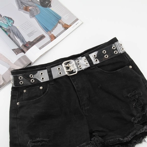 Cintura punk in PVC trasparente con doppi occhielli e fibbia argento su pantaloncini denim