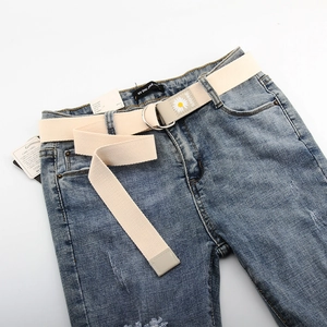 Détail d'une ceinture en toile crème avec motif marguerite et boucle en double D