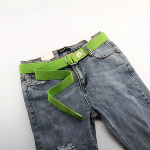 Détail de la ceinture en toile verte avec broderie marguerite et boucle à double anneau