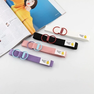 Close-up of four candy-colored canvas belts with double D-ring buckles and duck patch