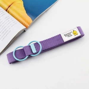 Detail of purple canvas belt with light blue double D-ring buckle and cartoon duck tag