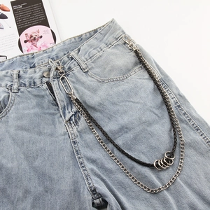 Close-up of double-layer silver metal chain and black woven leather pants chain on denim
