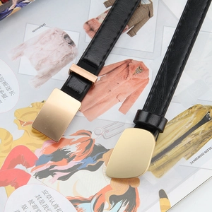 Two black thin leather belts with minimalist gold buckles on a stylish fashion magazine