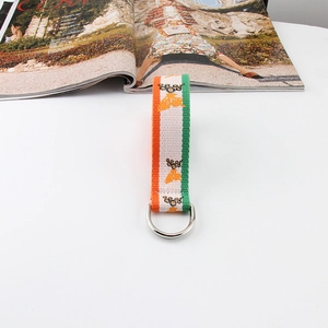 Close-up of orange butterfly print on striped canvas webbing with silver D-ring buckle