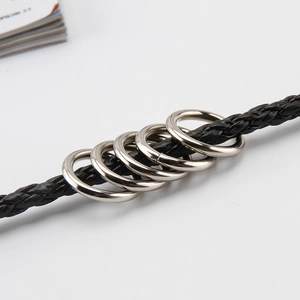 Close-up of polished silver metal rings on a black braided leather belt chain