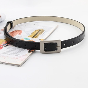 Detail of slim black belt with silver rectangular metal buckle on a fashion magazine
