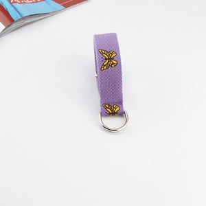Detail of purple canvas belt featuring yellow butterfly embroidery and silver D-ring