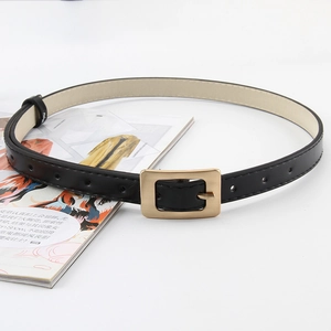 Detail view of a slim black leather belt with a golden rectangular pin buckle on white back