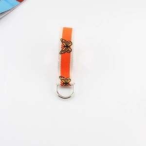 Detail view of the cream canvas belt featuring orange stripes and butterfly print with D-ring