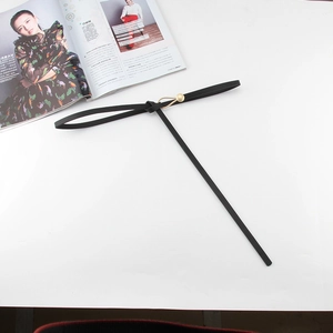 Détail d'une fine ceinture noire avec boucle dorée en forme de nœud goutte d'eau