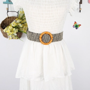 Detail of bohemian woven belt with black and white herringbone pattern and round wooden buckle