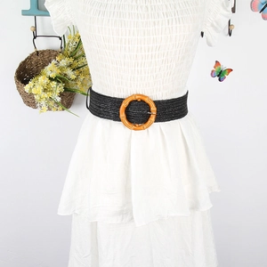 Detail of black woven elastic belt featuring a round natural bamboo buckle on a dress