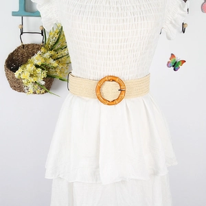 Detail of bohemian straw woven belt with round bamboo buckle on white pleated dress