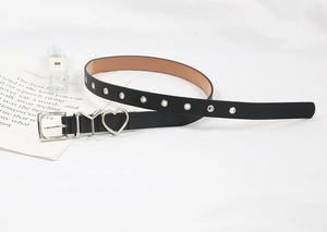 Détail de ceinture noire en cuir avec pendentif cœur argenté et boucle en métal en Y