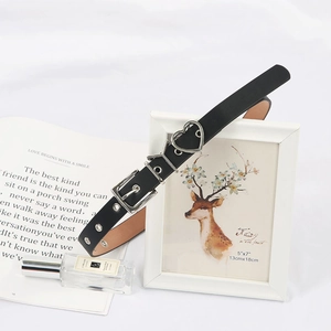 Détail d'une ceinture noire en cuir avec boucles métalliques en cœur et lettre Y