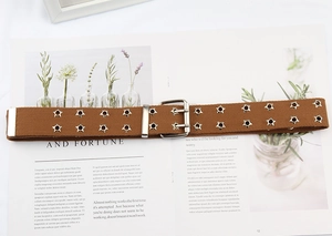 Detail of brown canvas belt with double row star grommets on vintage magazine backdrop