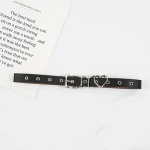 Détail de la ceinture noire avec pendentif cœur en argent et œillets métalliques sur blanc