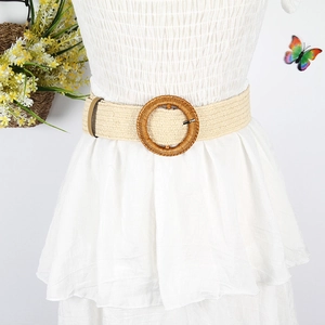 Detail of a woven waist belt with a round buckle on a white pleated dress in boho style
