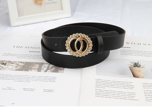 Détail d'une ceinture en cuir noir avec boucle dorée à double cercle sertie de strass