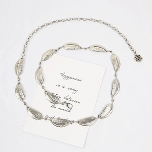 Vue détaillée d'une ceinture chaîne argentée à feuilles avec fermoir et pendentif rose